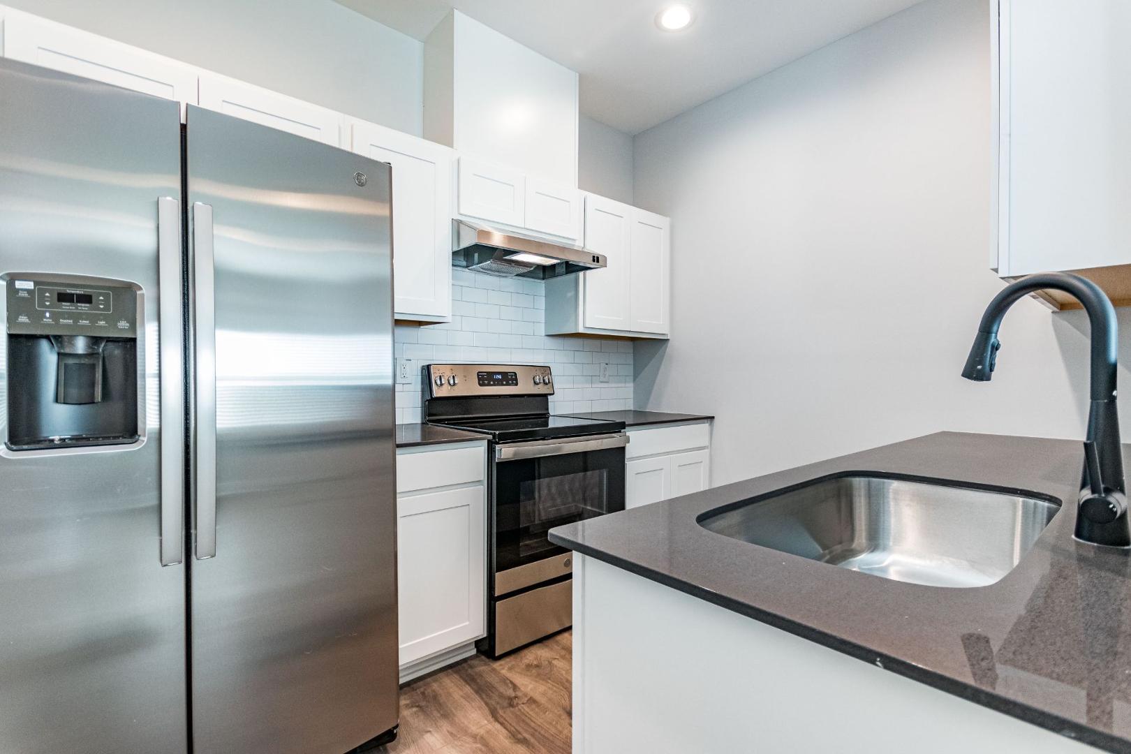 a kitchen with stainless steel appliances granite countertop a sink and a refrigerator