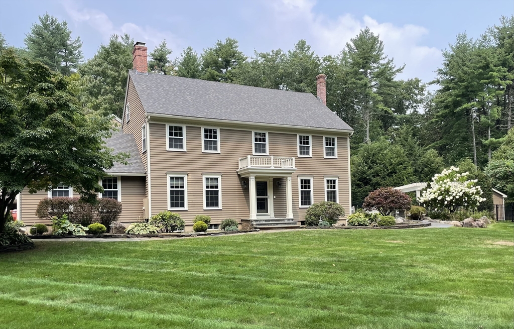 a front view of a house with a garden and trees