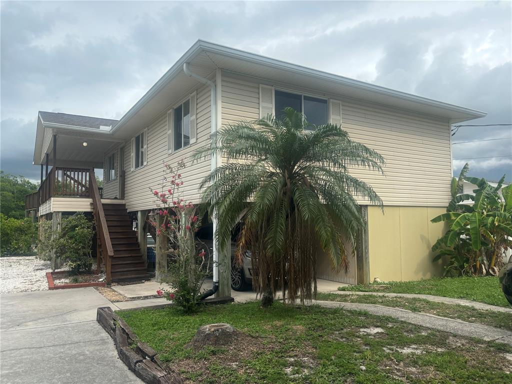 front view of house with a yard and palm trees