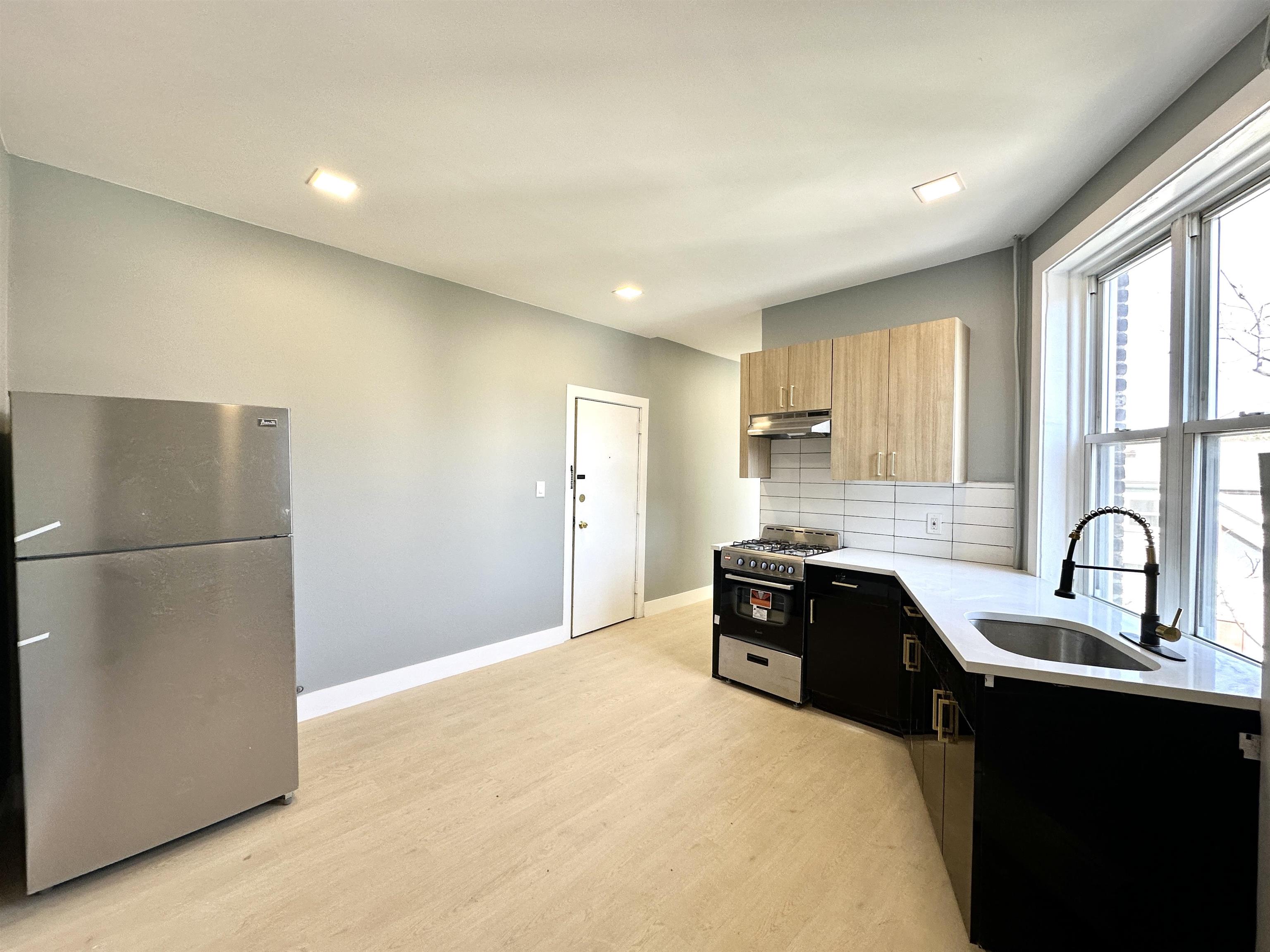 a kitchen with granite countertop a refrigerator stove and sink