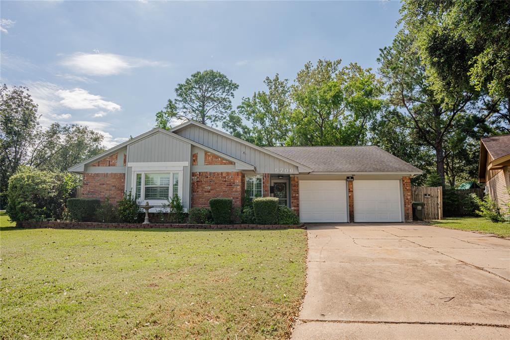 a front view of house with yard and trees in the background