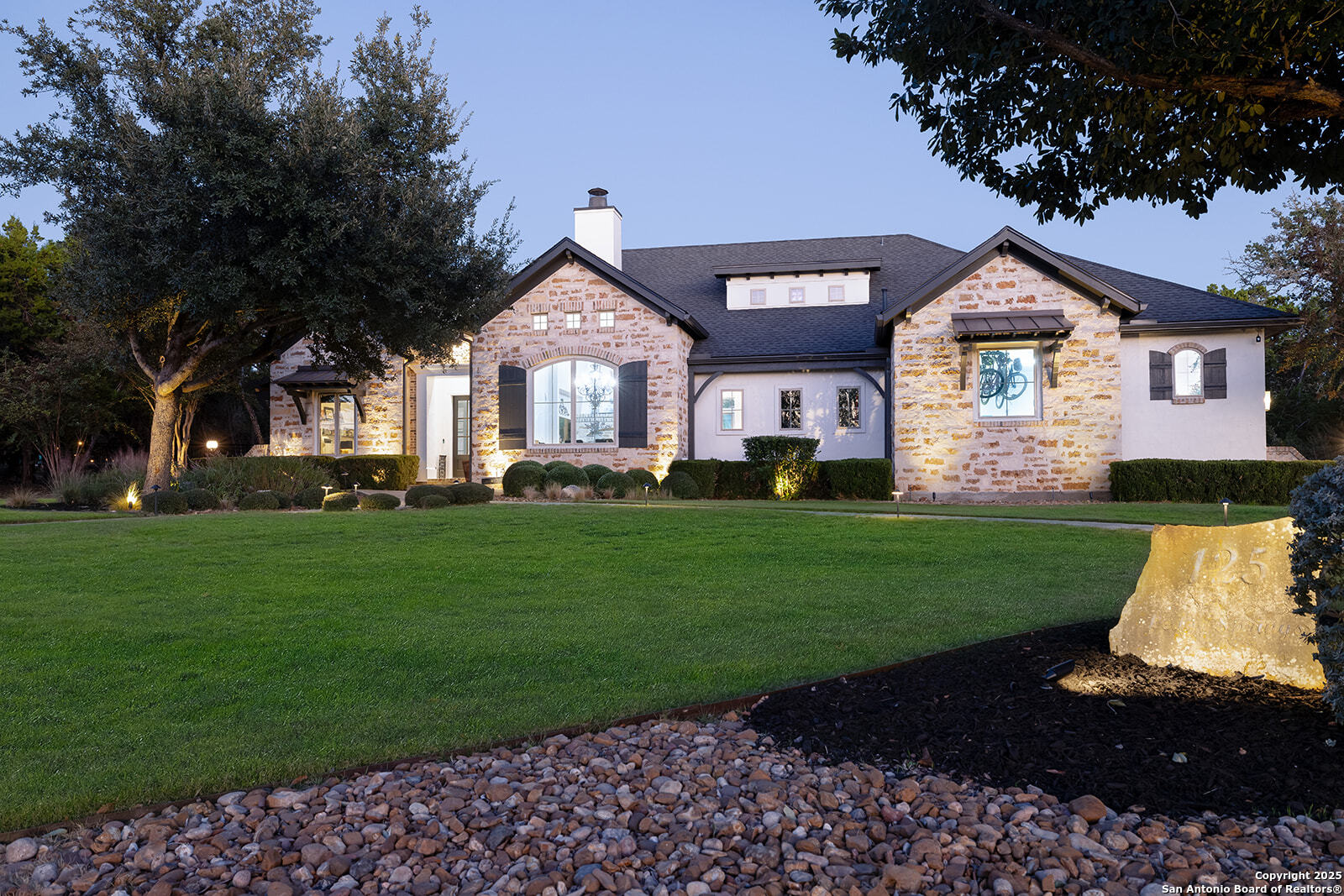 a front view of a house with a garden and trees