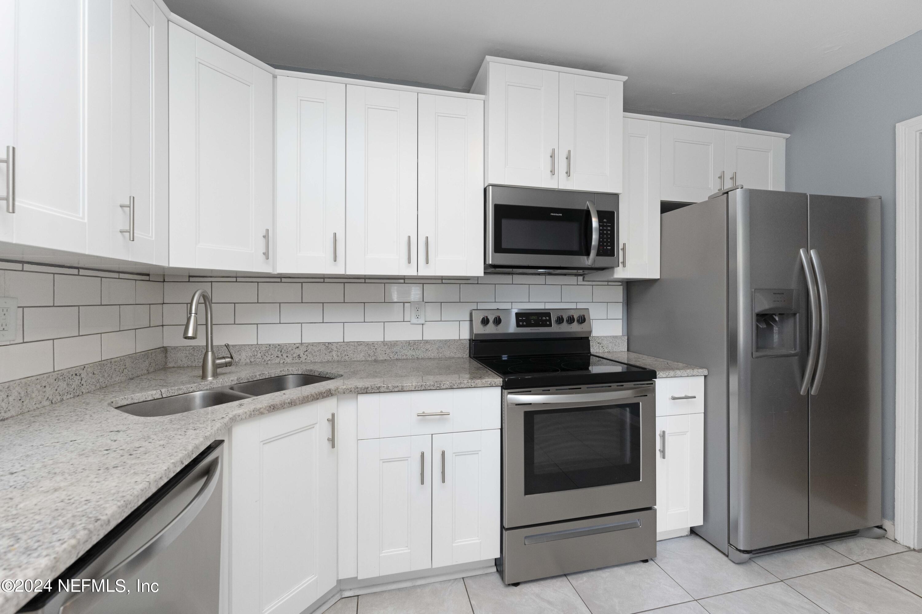 a kitchen with granite countertop white cabinets and stainless steel appliances