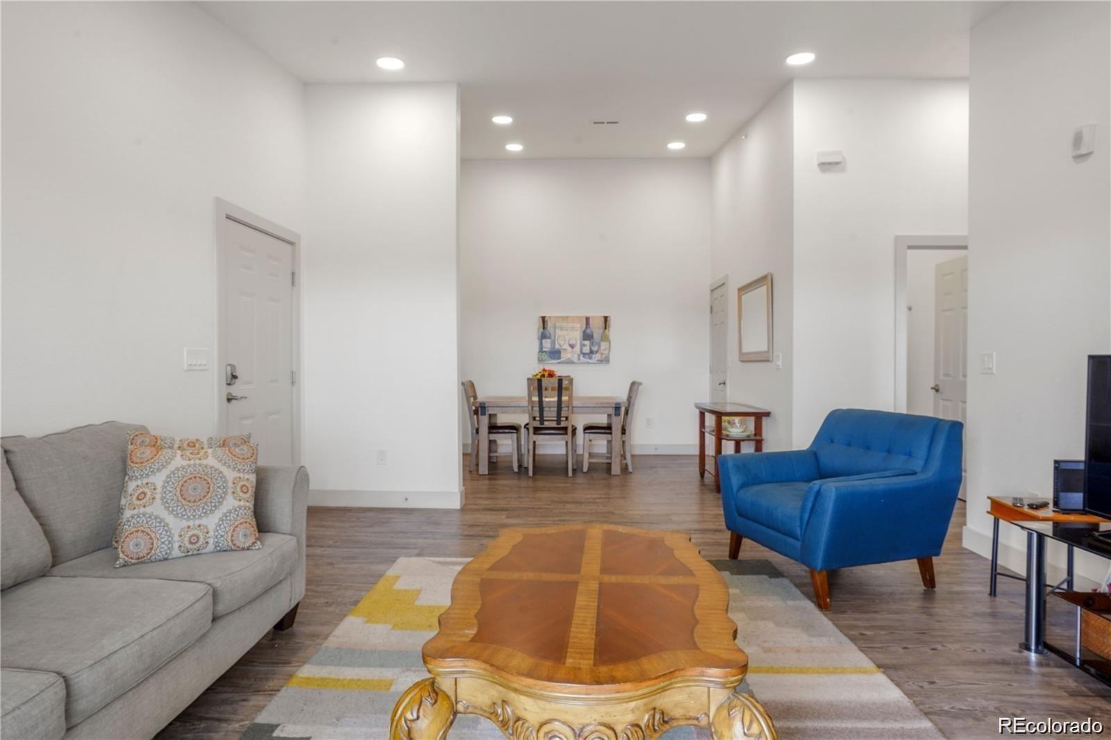 a living room with furniture and a dining table with a chandelier