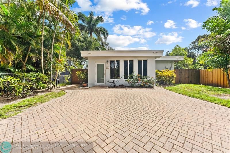 a front view of a house with a yard and potted plants