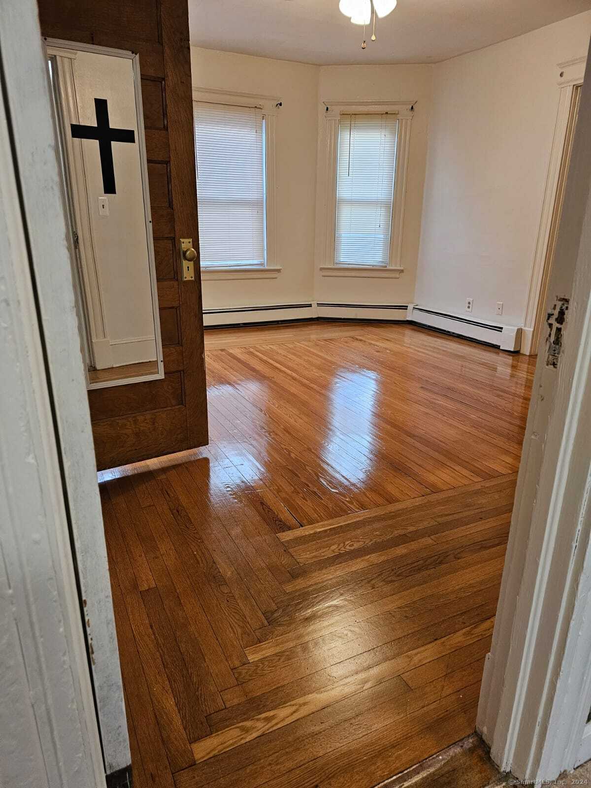 a view of an empty room with wooden floor and a window