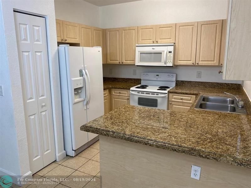 a kitchen with granite countertop a refrigerator and a stove