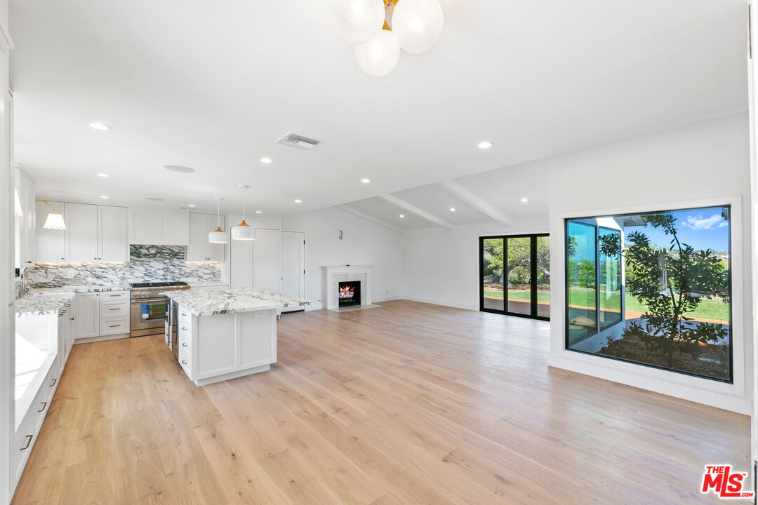 a view of open kitchen with white cabinets and wooden floor