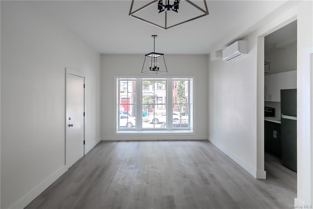 a big room with wooden floor chandelier and windows