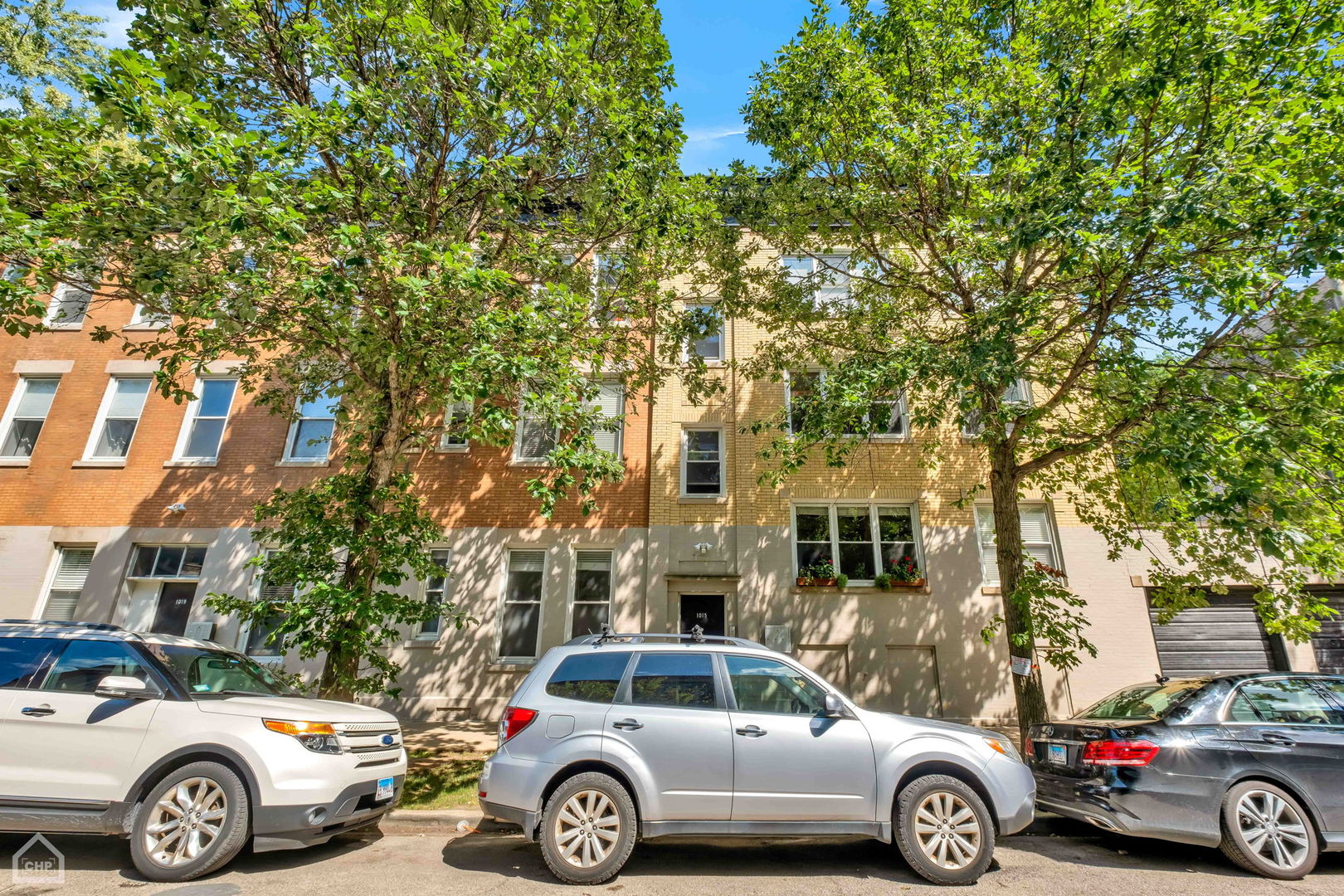 a front view of a residential apartment building with car parked