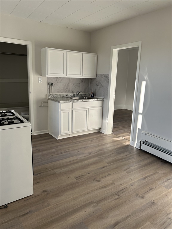 a kitchen with granite countertop wooden floors white cabinets and stainless steel appliances