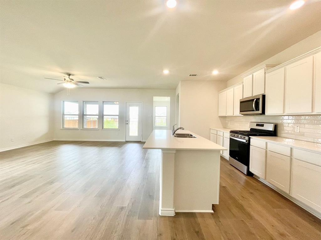 a large kitchen with stainless steel appliances granite countertop a stove a sink dishwasher and a oven with white cabinets