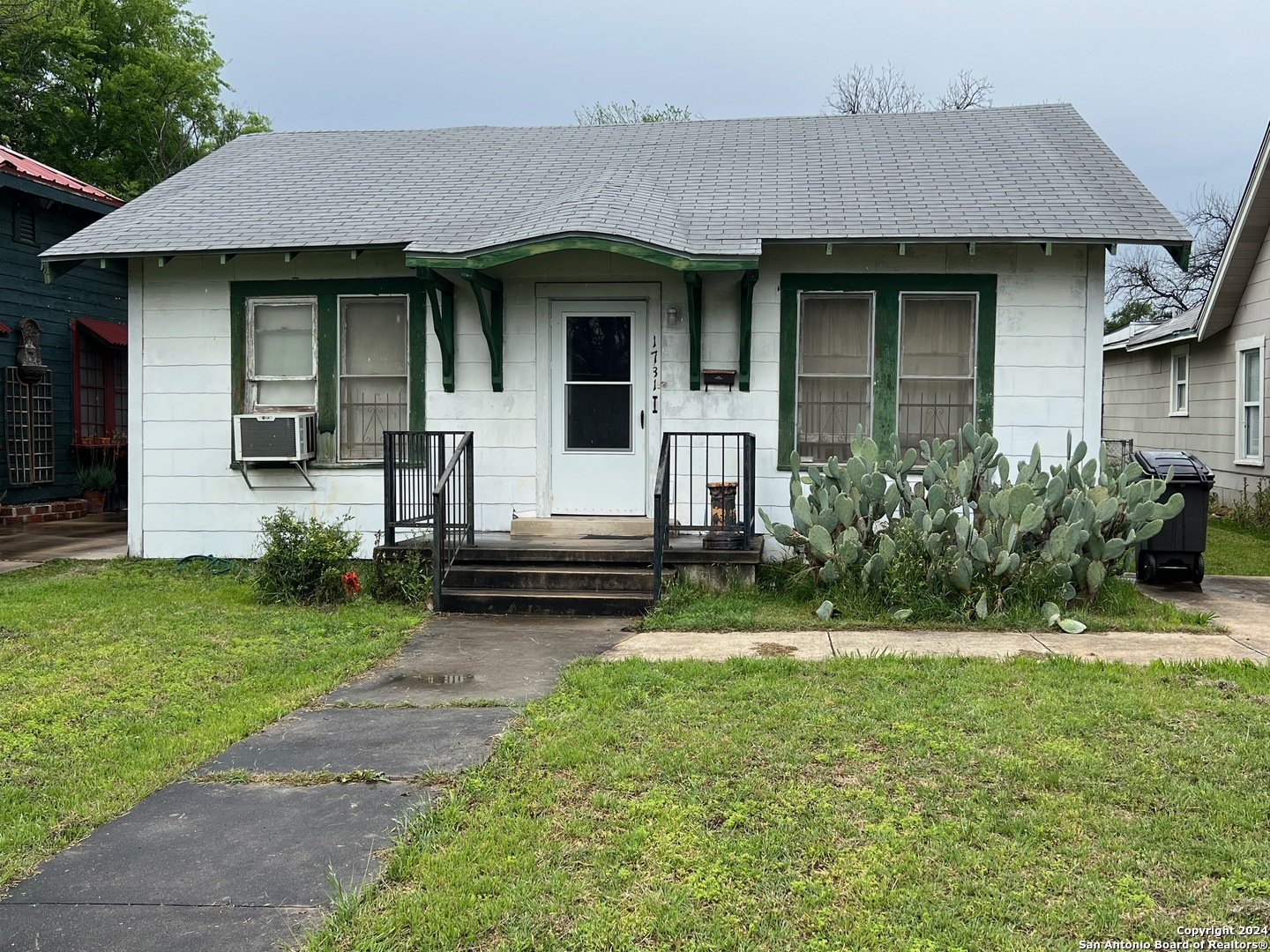 a view of a house with a yard plants and large tree