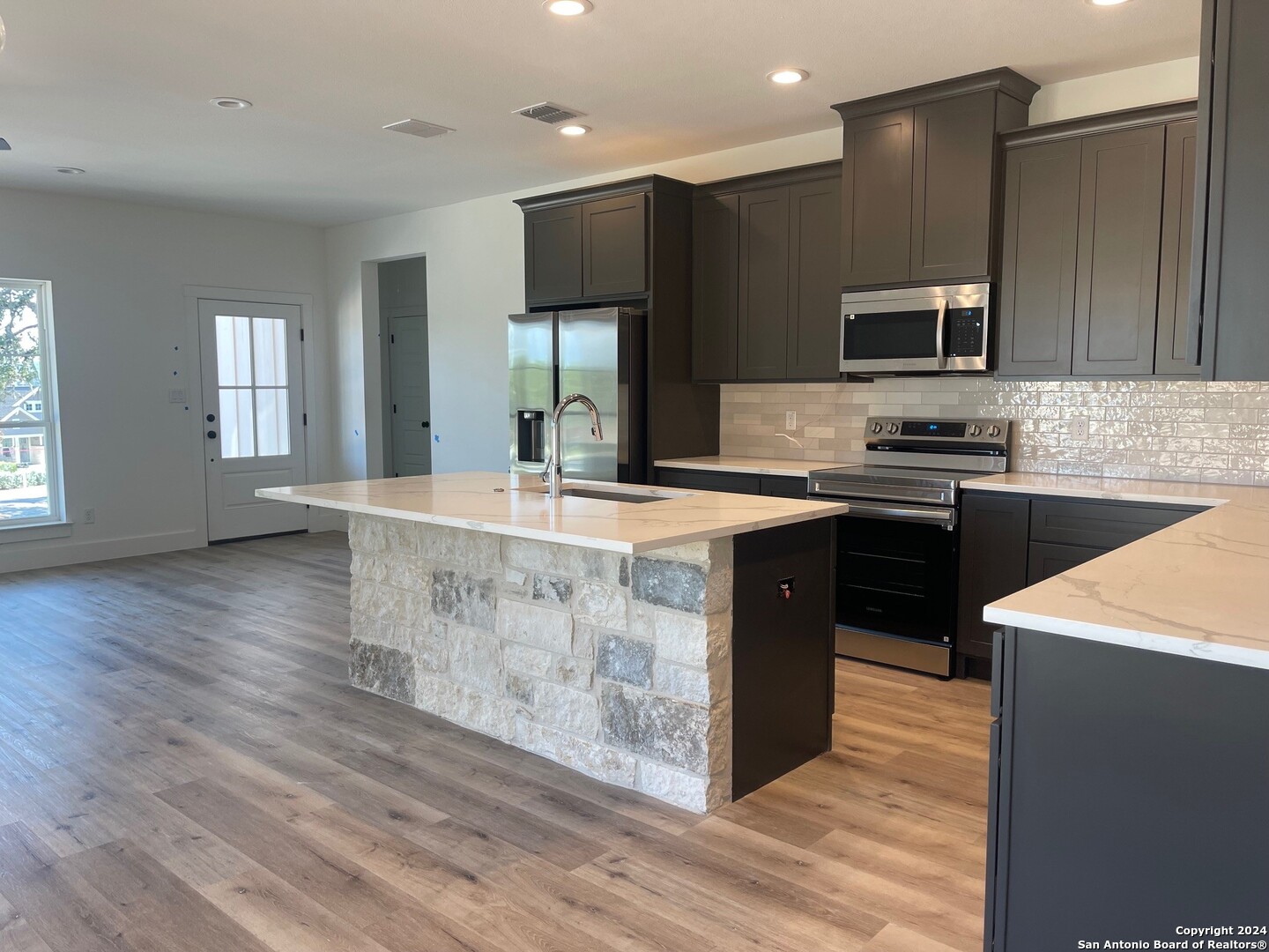 a kitchen with stainless steel appliances granite countertop a sink a stove and a wooden floors