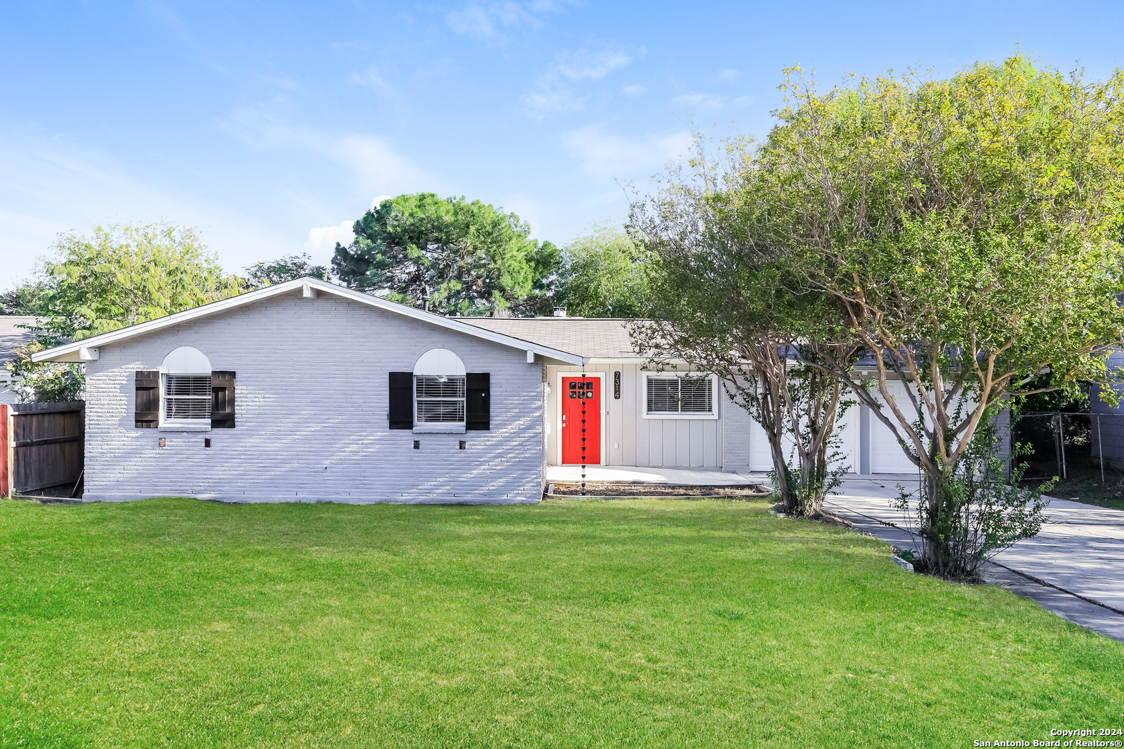 a front view of house with yard and trees in the background