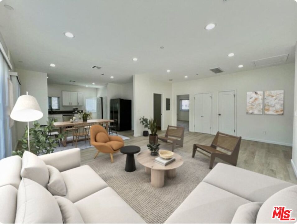 a living room with furniture kitchen view and a large window