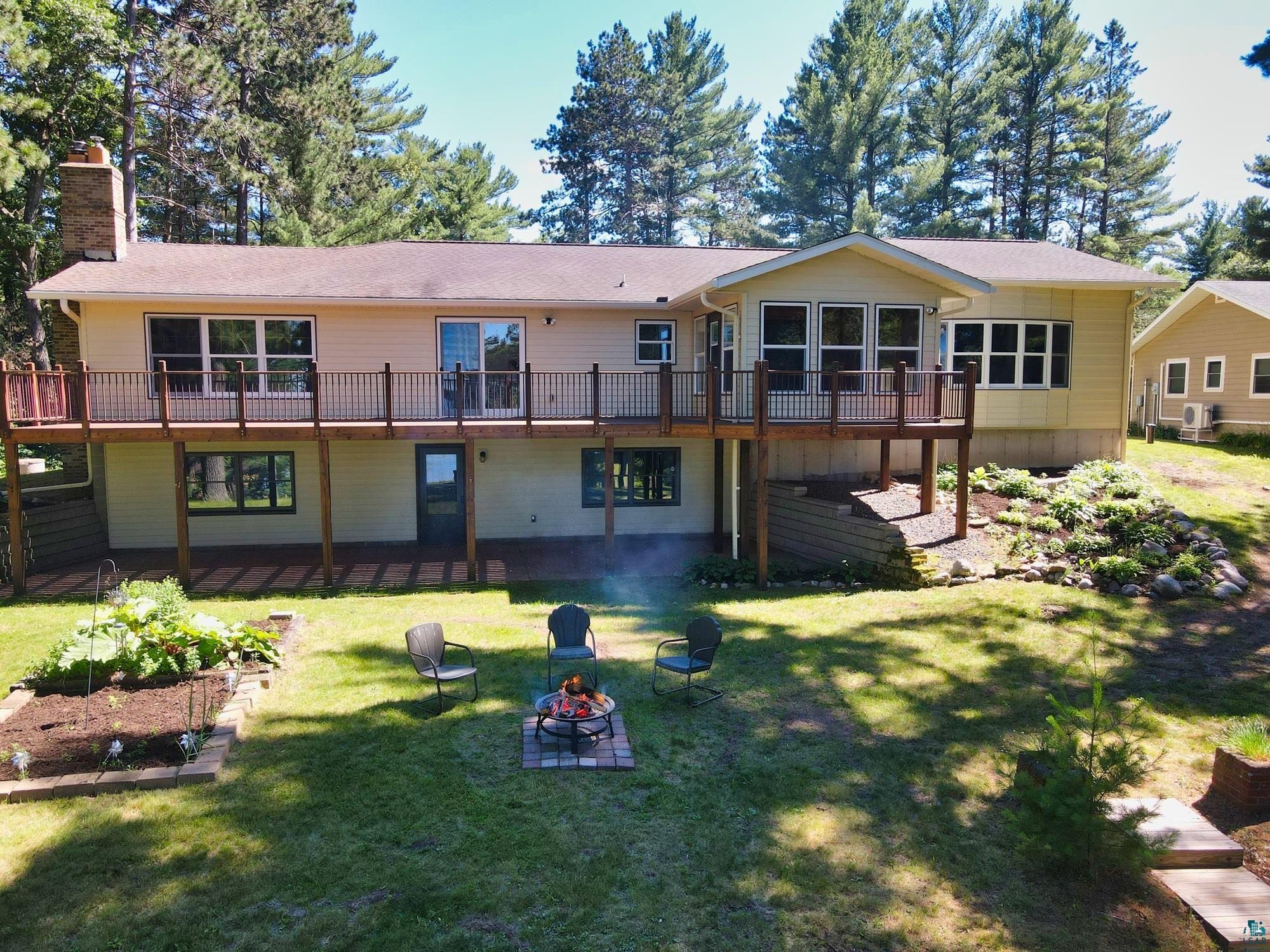 Rear view of house featuring a deck, a yard, and an outdoor fire pit