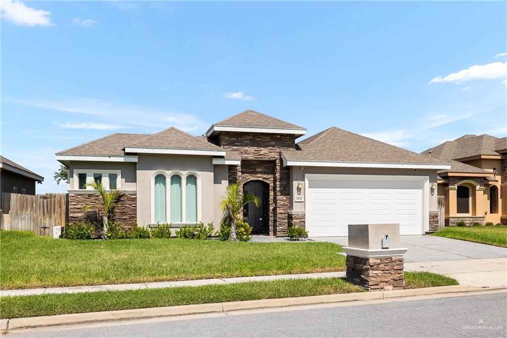 View of front facade featuring a garage and a front lawn