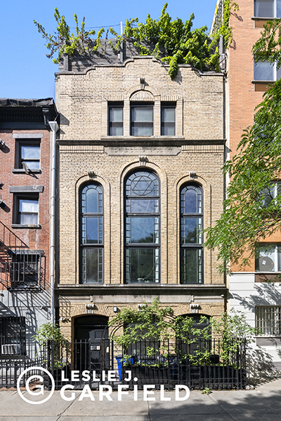 a front view of a building with lots of trees and flowers