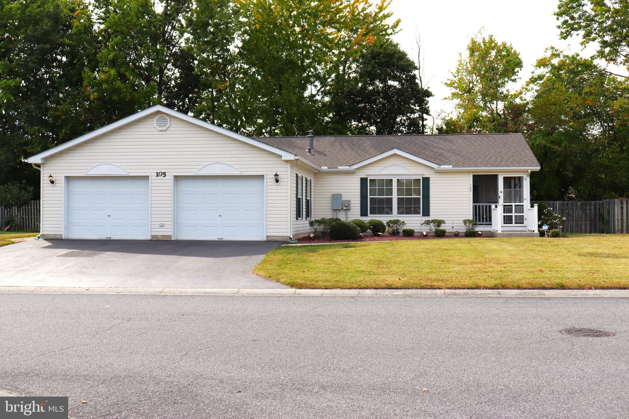 a front view of a house with a yard and trees all around