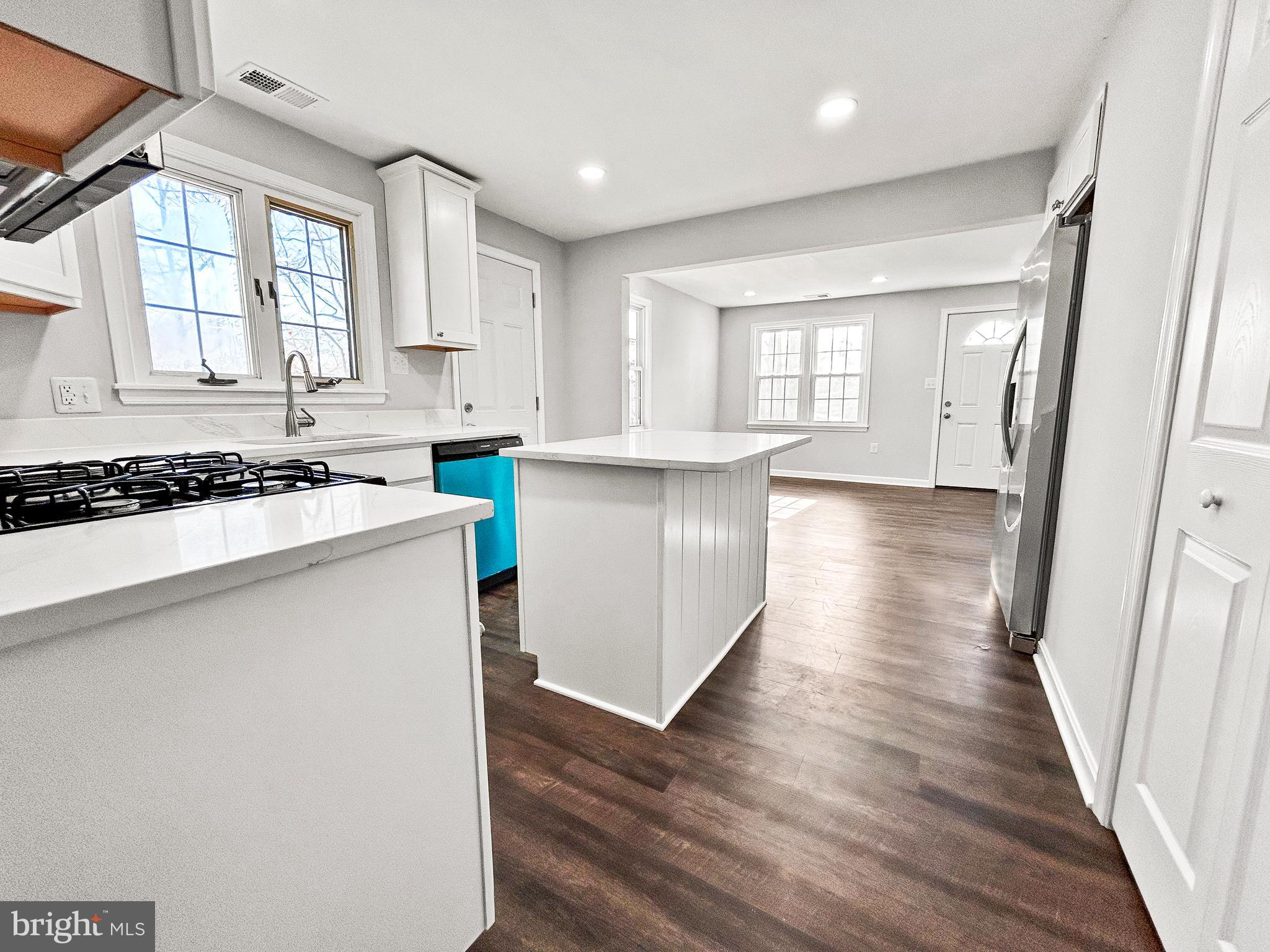 a kitchen that has a lot of cabinets a stove and wooden floor