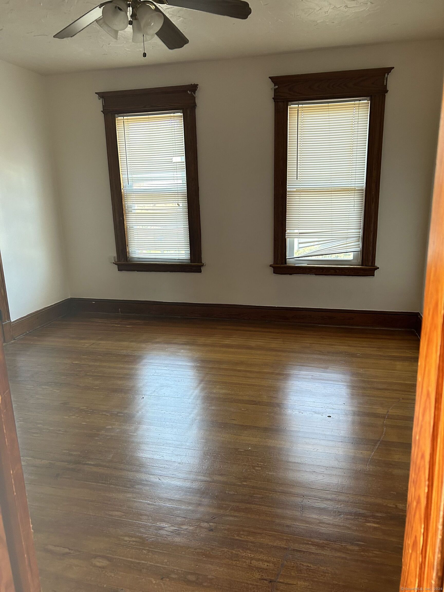 an empty room with wooden floor and windows