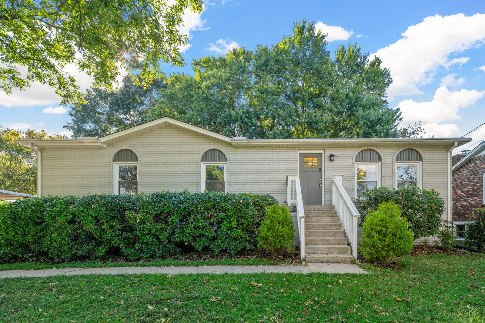 a front view of a house with a yard and trees