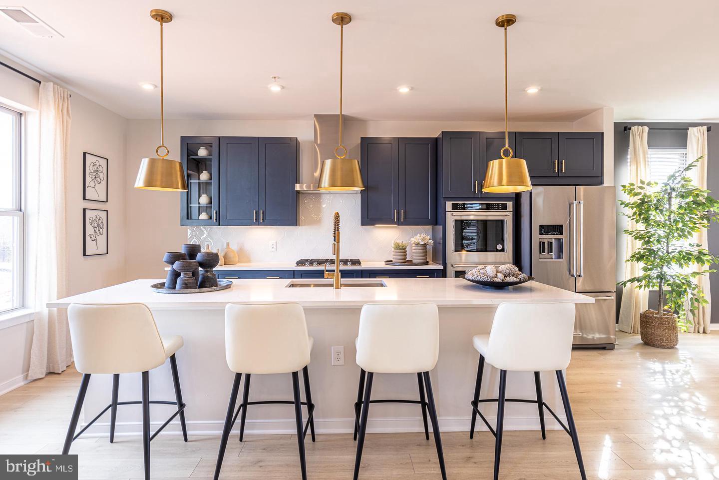 a kitchen with stainless steel appliances a dining table chairs refrigerator and sink