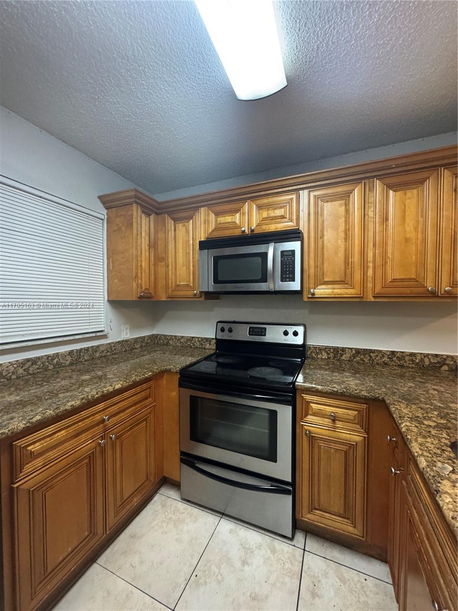 a kitchen with granite countertop a stove top oven microwave and cabinets