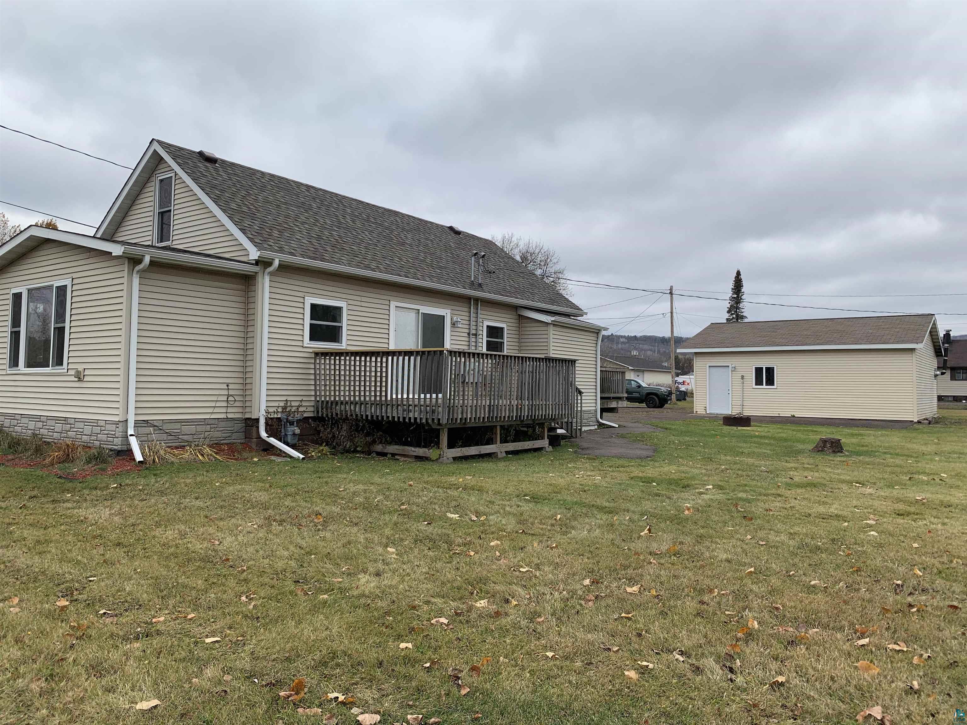 Back of property featuring a wooden deck and a yard