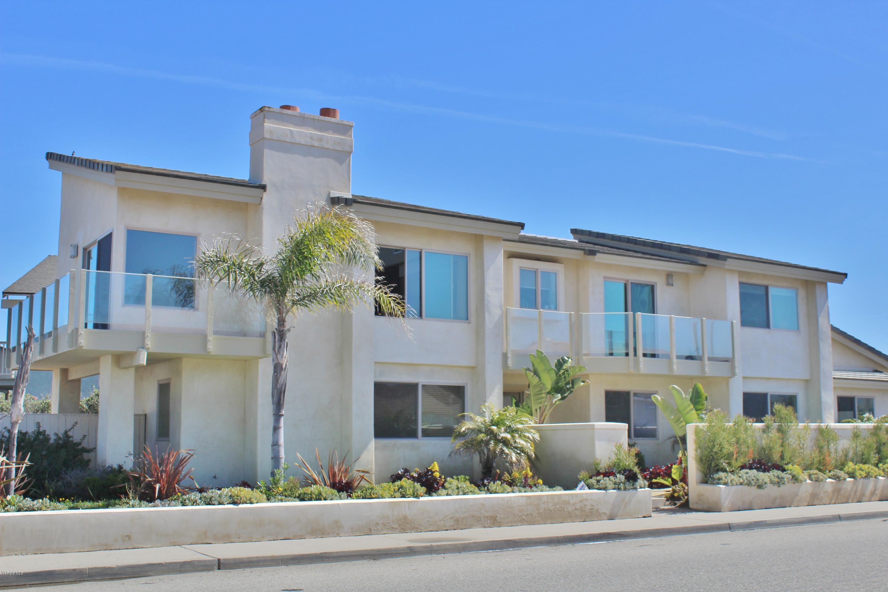 a front view of a multi story residential apartment building with yard and parking