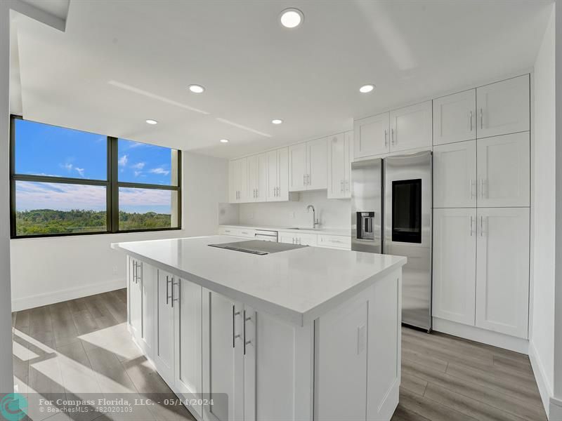 a kitchen with a sink a counter top space stainless steel appliances and a large window