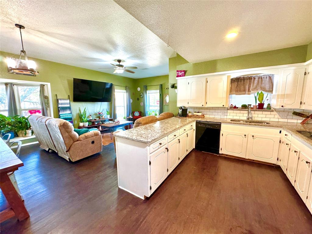 a large white open kitchen with stainless steel appliances kitchen island a stove a sink dishwasher a dining table and chairs with wooden floor