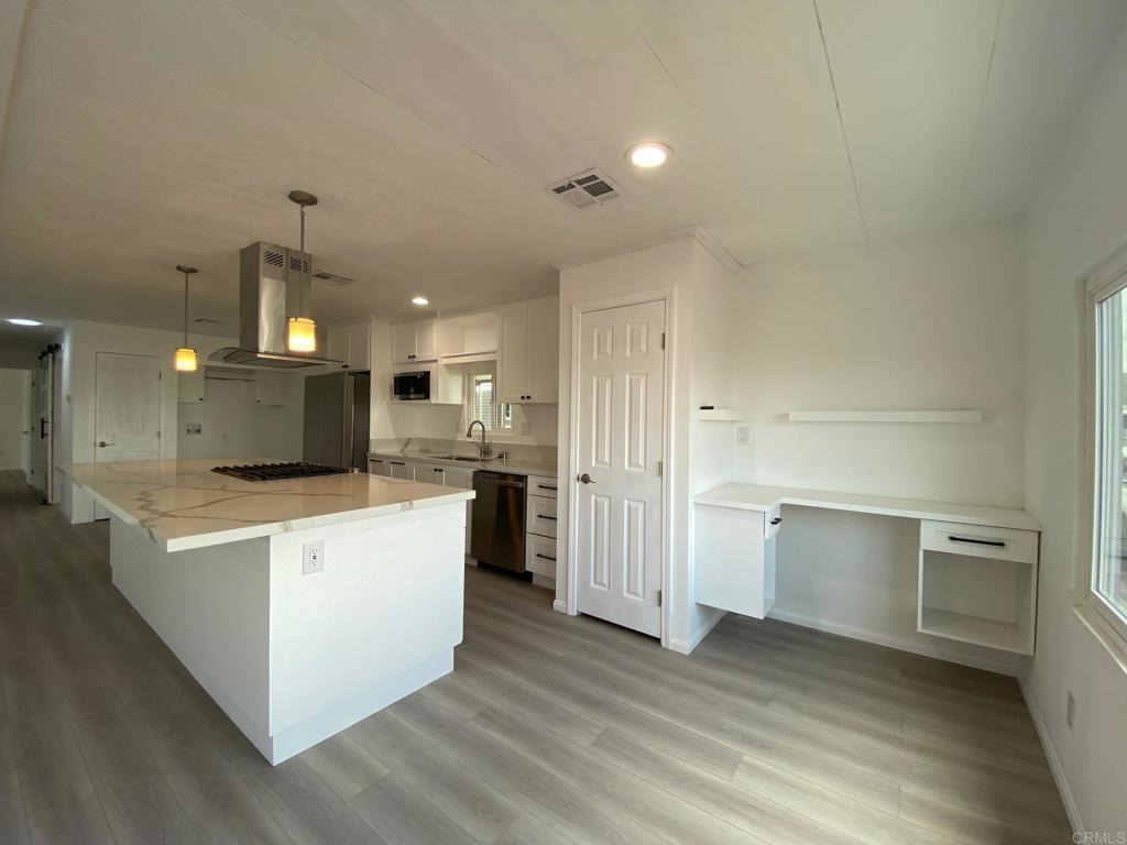 a large kitchen with a center island and stainless steel appliances