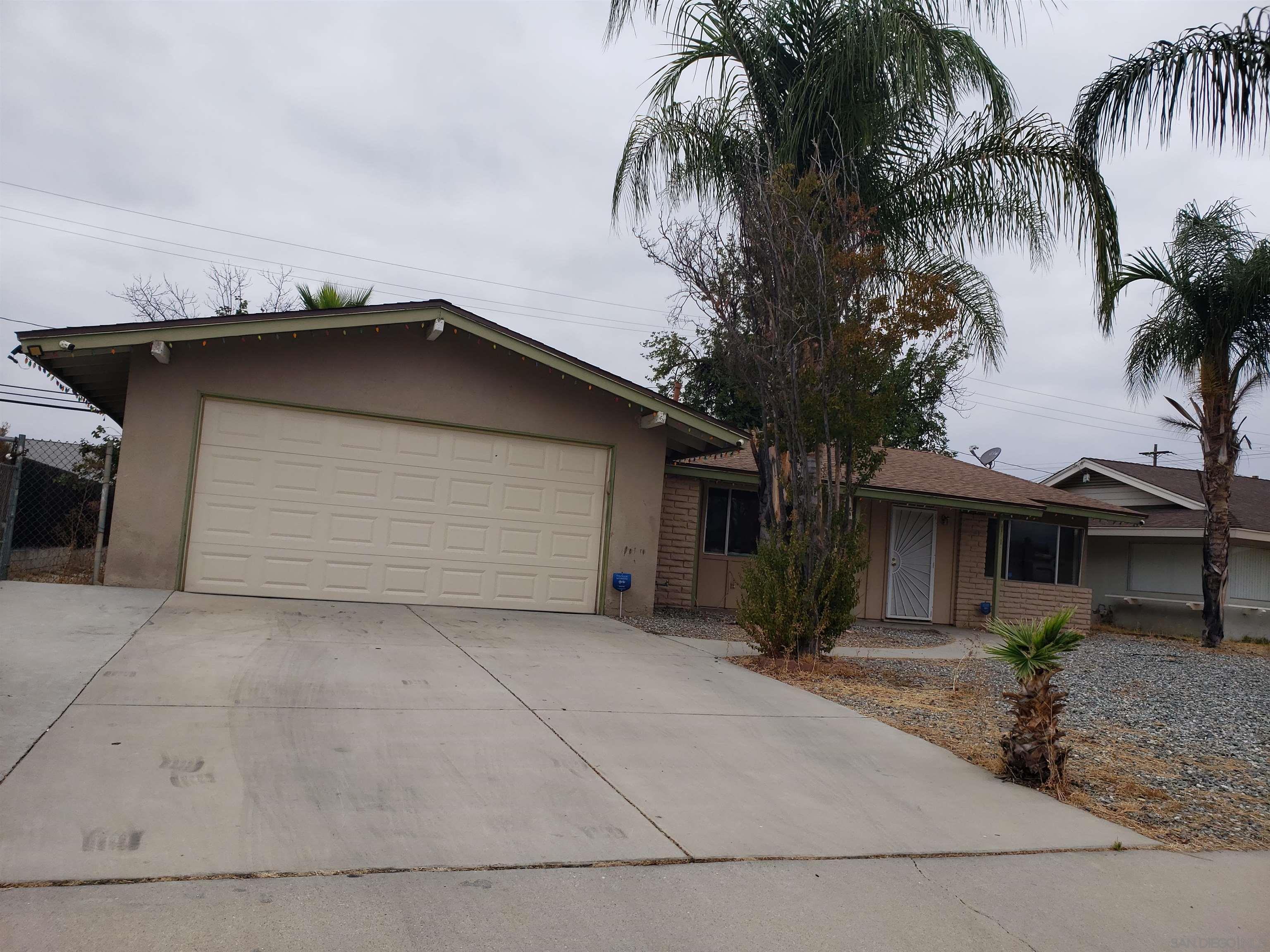 a backyard of a house with potted plants and palm trees