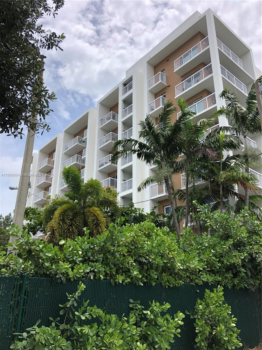 a view of a building with plants and large trees