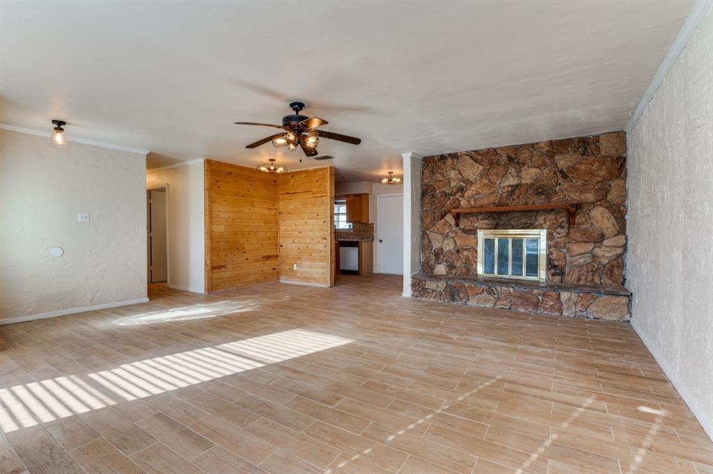 Unfurnished living room with ceiling fan, a fireplace, light hardwood / wood-style floors, and ornamental molding