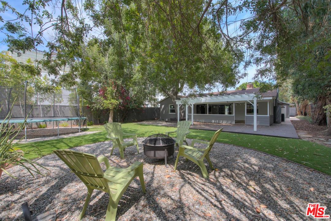 a view of a chair and table in backyard of the house