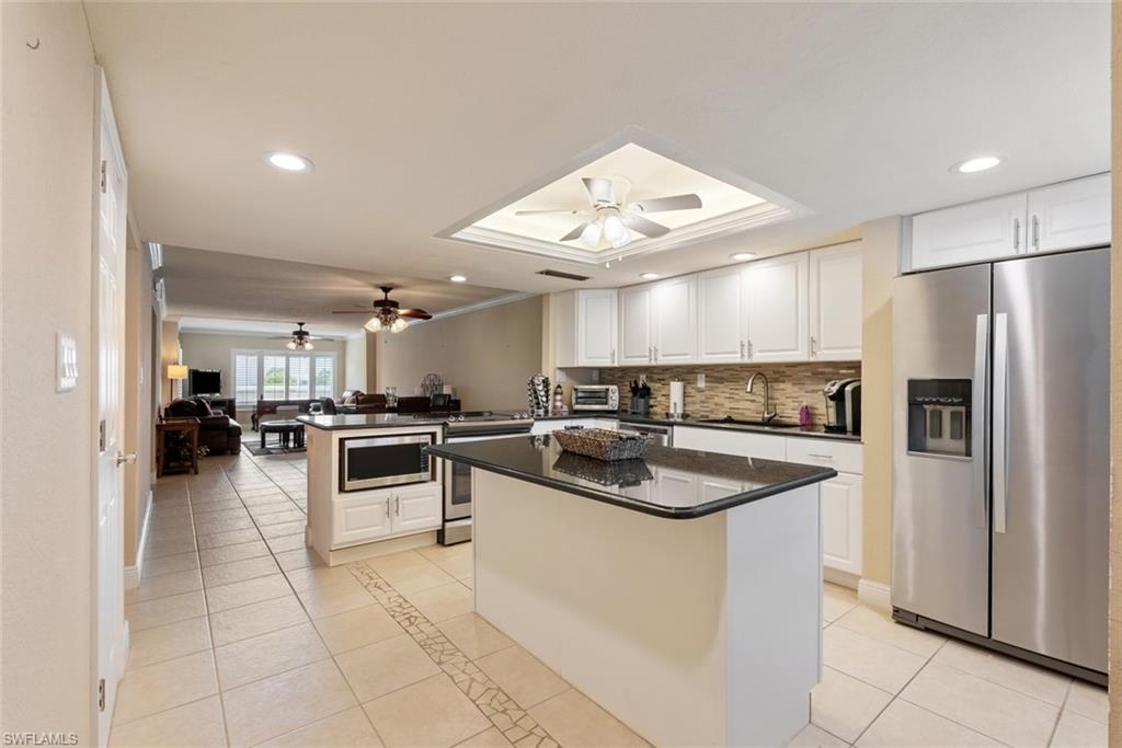 Kitchen featuring ceiling fan, stainless steel appliances, a center island, sink, and white cabinetry