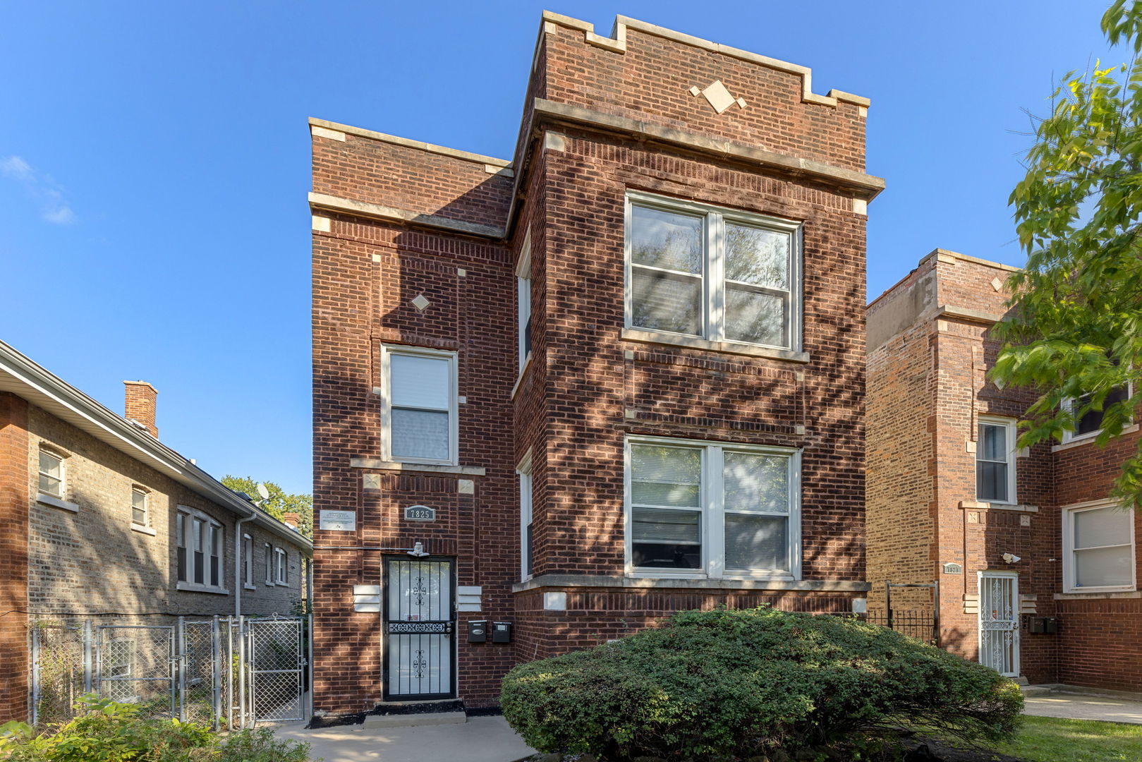 a front view of a residential apartment building with a tree