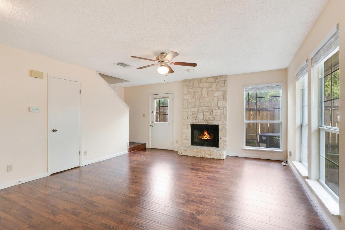 an empty room with large windows fireplace and wooden floor