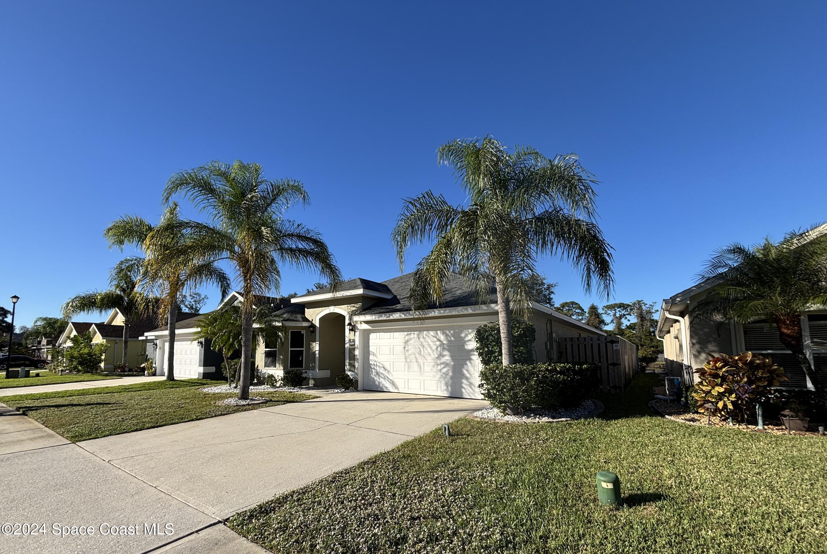 a front view of a house with a yard and potted plants