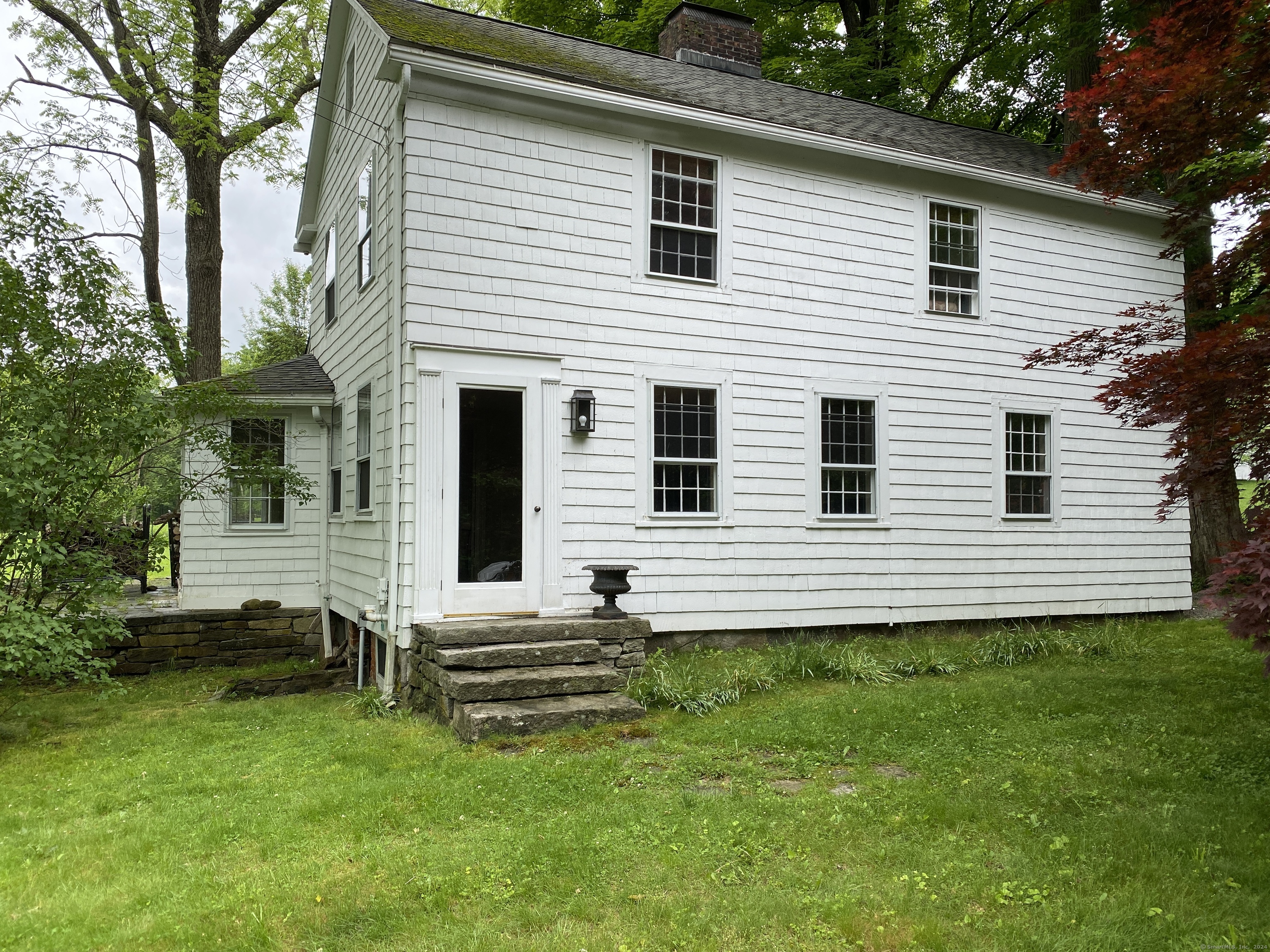 a view of a house with a yard and a large tree