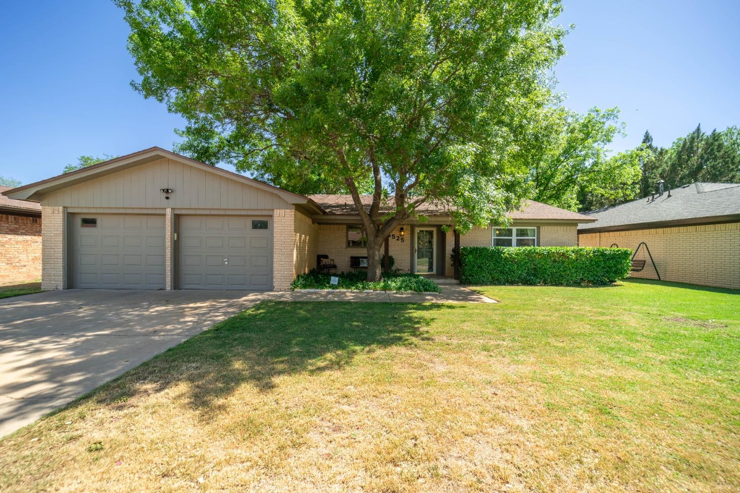 a view of a house with a yard and large tree