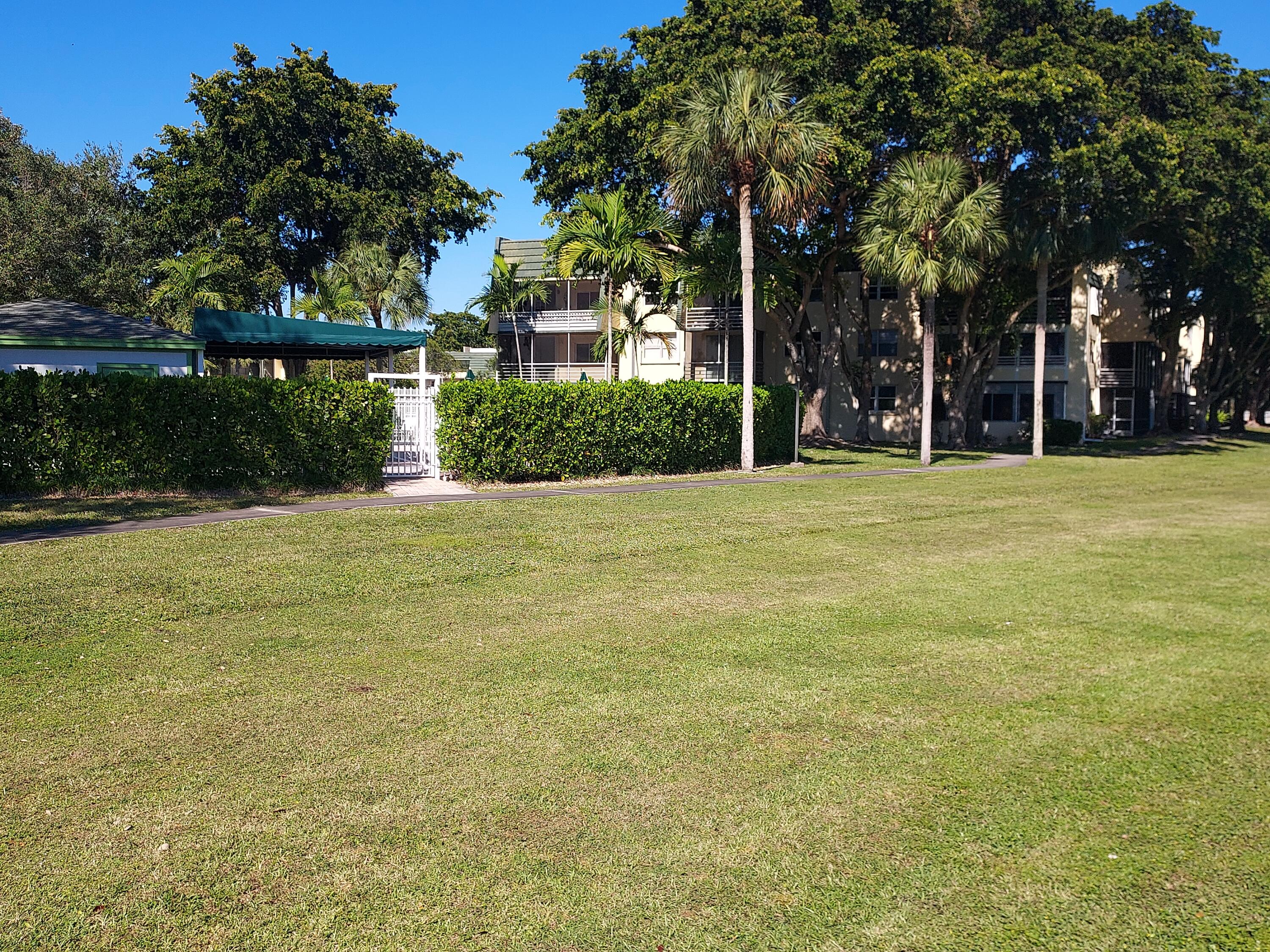 a front view of a house with a big yard and palm trees