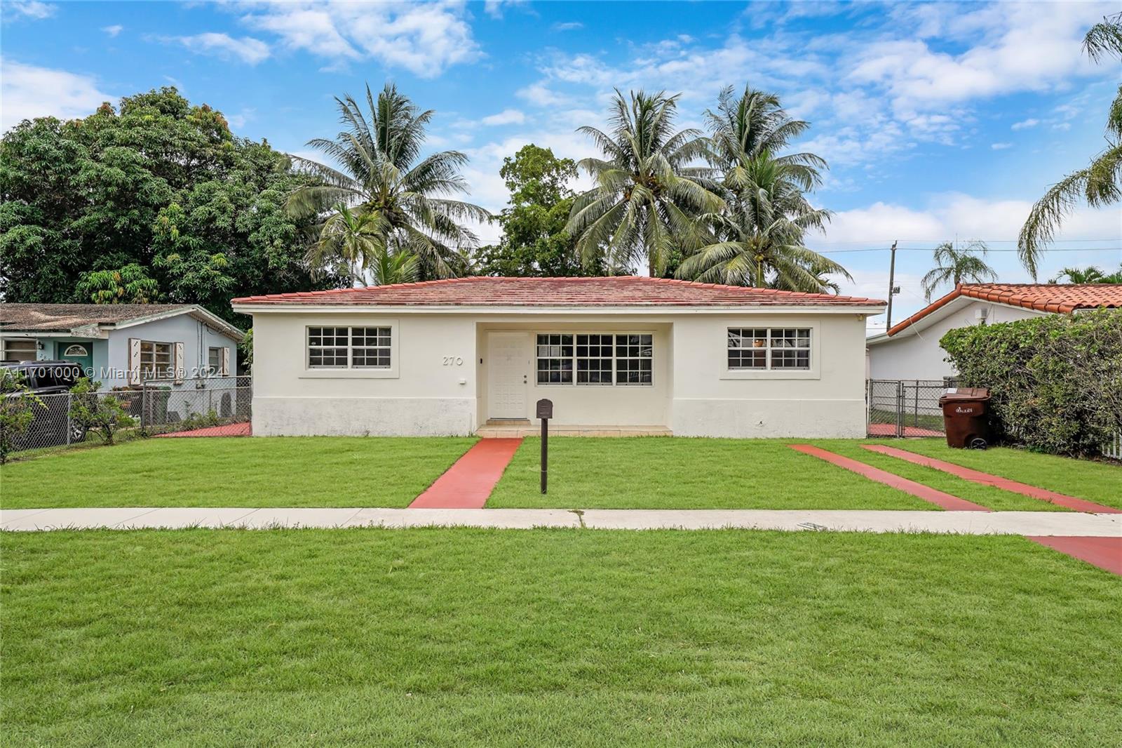 a view of a house with a yard and palm trees