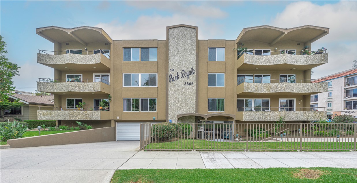 a front view of a residential apartment building with a yard and potted plants