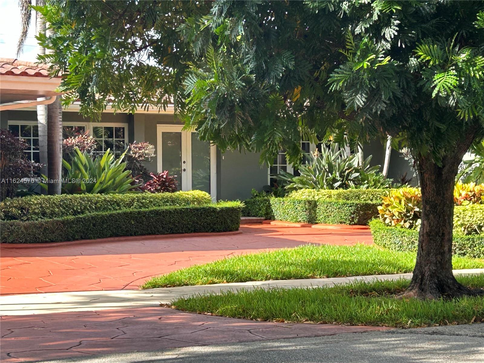 a front view of a house with a yard and potted plants