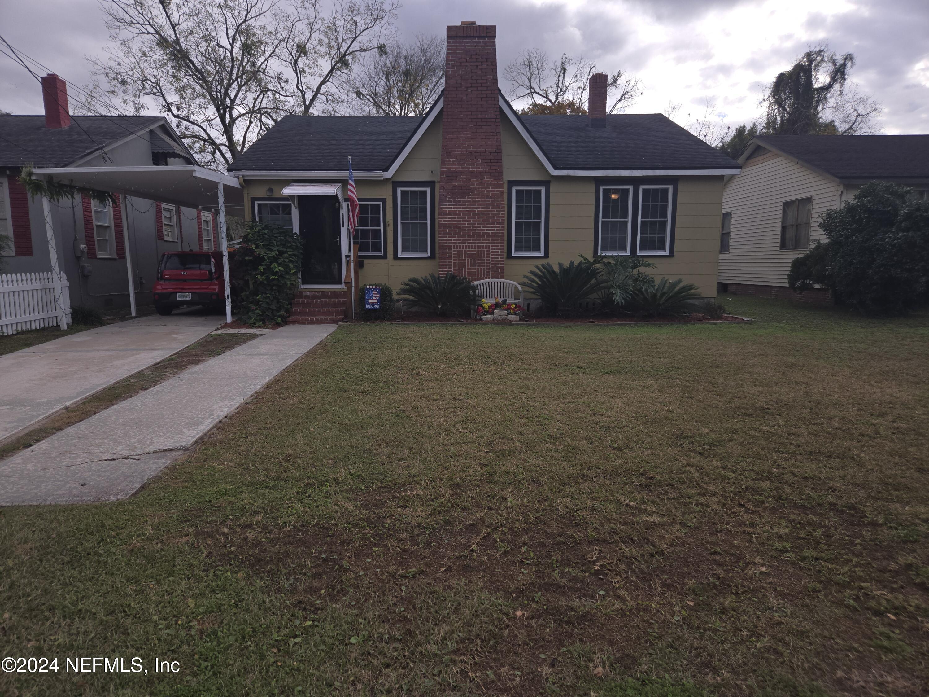 a view of a brick house next to a yard with large tree