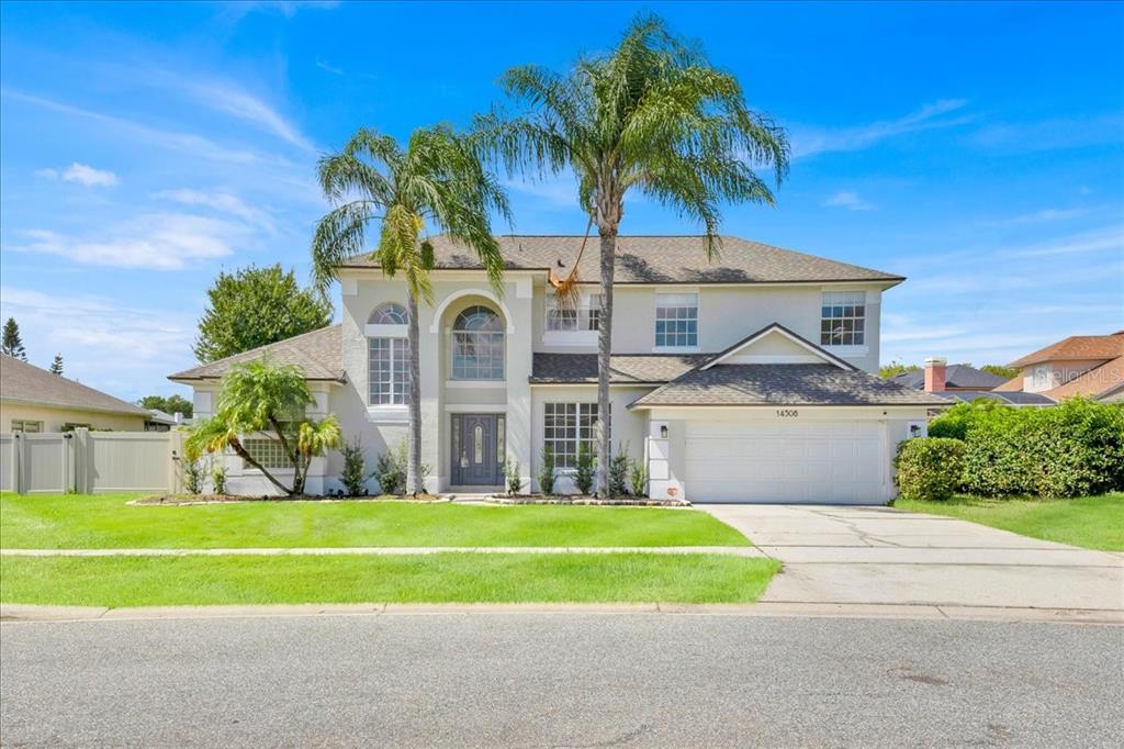 a front view of a house with plants and palm trees